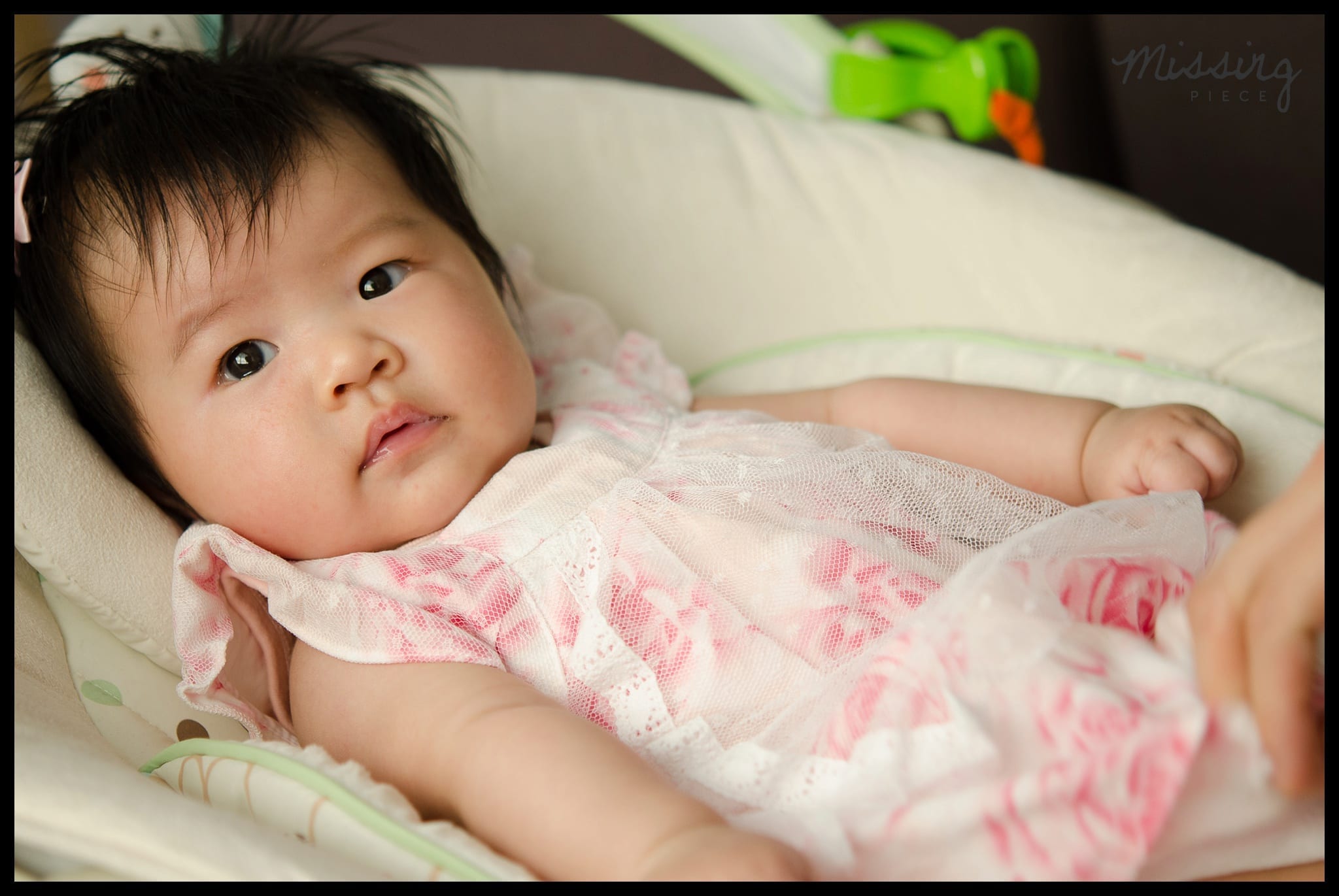 Baby looks at the camera as she sits on her crib